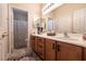 Bathroom with double sinks, wooden cabinets, and a shower with a patterned curtain at 1413 Gentle Brook St, North Las Vegas, NV 89084