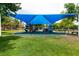 Community playground shaded by a bright blue sunshade canopy, surrounded by green grass and trees at 1413 Gentle Brook St, North Las Vegas, NV 89084