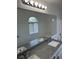 Bathroom mirror reflecting double sinks with granite countertop, tub/shower and bright vanity lighting at 1511 Balsam Mist Ave, Las Vegas, NV 89183