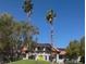 Charming desert home featuring solar panels, tile roof, and front yard palm trees at 1871 Ski Slope Cir, Las Vegas, NV 89117