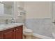 Well-lit bathroom featuring marble tile, a wood vanity, and a white toilet at 2555 Antique Blossom Ave, Henderson, NV 89052