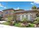 Elegant home showcasing arched windows, a three-car garage, lush landscaping, and a well-maintained lawn at 2577 Luberon Dr, Henderson, NV 89044