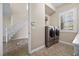 Bright laundry area by stairs features front load machines and a view to the outside at 2577 Luberon Dr, Henderson, NV 89044