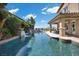Resort-style pool with waterfalls, landscaped greenery, and a covered patio for outdoor dining and entertaining at 2577 Luberon Dr, Henderson, NV 89044