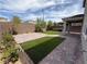 Spacious backyard featuring a covered patio, artificial grass, and manicured shrubbery at 2620 Tolmezzo St, Henderson, NV 89044