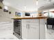 Stylish kitchen island featuring granite countertops, a built-in wine cooler, and sleek white cabinetry at 30 Via Vasari # 103, Henderson, NV 89011