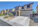 Two-story home featuring a beige exterior, rock accents, attached two-car garage, and well-maintained landscaping at 405 Prairie Moon Ave, North Las Vegas, NV 89084