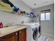 This laundry room features lots of shelving, washer, dryer, and sink at 405 Prairie Moon Ave, North Las Vegas, NV 89084