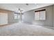 Spacious living room featuring neutral paint, plush carpet, ceiling fan, and natural light from multiple windows at 405 Prairie Moon Ave, North Las Vegas, NV 89084