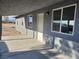 View of the covered patio featuring grey exterior walls, multiple windows and concrete flooring at 4231 E Kellogg Rd, Pahrump, NV 89061