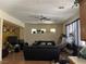Comfortable living room with neutral walls, ceiling fan, dark sofas, and ample natural light from multiple windows at 5043 Gable Crest Ct, Las Vegas, NV 89141