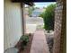 View of brick and stucco walkway leading to house with mature plants and rock landscaping at 5821 Santa Catalina Ave, Las Vegas, NV 89108