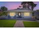 Charming single-story home with lush green lawn and inviting front porch at dusk at 615 D Ave, Boulder City, NV 89005