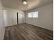 A bright bedroom showcasing wood-look floors, base moldings, a window and sliding-door closet at 6905 Singing Dunes Ln, Las Vegas, NV 89145