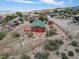 Charming red home featuring a deck and shed, nestled in a desert landscape with native plant life at 70 Camp Bonanza Rd, Las Vegas, NV 89124