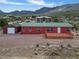 Charming home with a green roof, wooden deck, and detached garage, nestled against a mountain backdrop at 70 Camp Bonanza Rd, Las Vegas, NV 89124