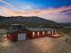 Exterior view of a red home with a detached garage and deck, set against a mountain landscape at 70 Camp Bonanza Rd, Las Vegas, NV 89124