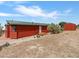 Exterior view of the red cabin shows the front entry, and surrounding desert landscape at 70 Camp Bonanza Rd, Las Vegas, NV 89124