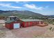 Exterior view of a red home with a detached garage and deck, set against a mountain landscape at 70 Camp Bonanza Rd, Las Vegas, NV 89124