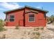 Up close exterior view of the red cabin shows windows and surrounding desert landscape at 70 Camp Bonanza Rd, Las Vegas, NV 89124