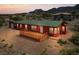 A single-story red home with a green roof and wooden deck, surrounded by desert landscaping at 70 Camp Bonanza Rd, Las Vegas, NV 89124