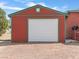 A red garage with green trim features a white door and gravel driveway at 70 Camp Bonanza Rd, Las Vegas, NV 89124