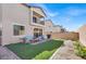 Expansive backyard with artificial grass, a second story balcony, and a built-in barbecue grill at 7107 Tilligerry St, North Las Vegas, NV 89084