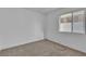 A bright, empty bedroom with tan carpet and a single window with natural light at 765 Butternut Ct, Henderson, NV 89014