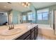 Bright bathroom with dual sinks, quartz countertops, soaking tub, and walk-in shower at 7761 Sagamore Bay Ct, Las Vegas, NV 89179