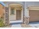 Close-up of front door with stone pillars and stylish exterior lighting fixtures at 7761 Sagamore Bay Ct, Las Vegas, NV 89179