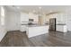 Bright, open kitchen featuring white cabinetry, gray countertops, and stainless steel appliances with gray wood flooring at 7777 Vino Vranec Ct, Las Vegas, NV 89113