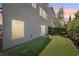 View of the home's backyard with artificial turf, neutral-tone exterior, and partial fence at 8042 Misty Canyon Ave, Las Vegas, NV 89113