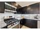 Close-up of a kitchen featuring stainless steel oven and microwave, granite countertop, and dark cabinets at 8042 Misty Canyon Ave, Las Vegas, NV 89113