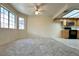 Bright living room featuring large windows, neutral carpet, and an adjacent kitchen area at 8410 Eldora Ave # 2046, Las Vegas, NV 89117