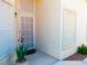 Home's entry features a white framed screen door, potted plant, and exterior lighting at 9705 Templemore Ave # 102, Las Vegas, NV 89129