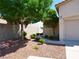 Landscaped front yard with green trees, small bushes, and decorative rock ground cover at 9705 Templemore Ave # 102, Las Vegas, NV 89129