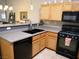 Stylish kitchen with light wood cabinets, a black sink, and modern appliances at 9705 Templemore Ave # 102, Las Vegas, NV 89129