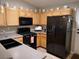 Traditional kitchen with light wood cabinets, black appliances, and ample countertop space at 9705 Templemore Ave # 102, Las Vegas, NV 89129