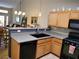 Well-lit kitchen featuring light wood cabinets, a black sink, and views of the dining and living area at 9705 Templemore Ave # 102, Las Vegas, NV 89129