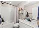 This bathroom features a shower-tub, white subway tile, a gray vanity with storage and framed mirror at 10101 Heron Lake Ave, Las Vegas, NV 89178