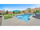 Inviting pool area with a sun umbrella, manicured lawn, and a soothing waterfall feature at 10601 Skye Arroyo Ave, Las Vegas, NV 89166