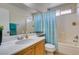 Bright bathroom features a shower over tub, tile surround, patterned shower curtain and a wood vanity with white counter at 11004 Napa Ridge Dr, Las Vegas, NV 89144