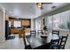 Open kitchen with wood cabinets and a black island adjacent to a formal dining area with black table at 11004 Napa Ridge Dr, Las Vegas, NV 89144