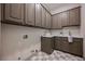 A spacious laundry room with brown cabinets, white counters, and a tiled floor at 2177 Magnolia Pond Ct, Henderson, NV 89052