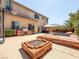 Spacious backyard patio with a stone fire pit, outdoor kitchen, and lush landscaping at 2382 Sunburst View St, Henderson, NV 89052