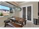 Bright dining area with modern chandelier, wood table and bench seating near a window and glass door at 2382 Sunburst View St, Henderson, NV 89052