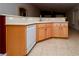 Functional kitchen area featuring light wood cabinets, a white dishwasher, and durable tile flooring at 2787 Sunken Ship St, Laughlin, NV 89029