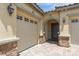 Close up view of a stucco home with an arched entryway framed by stone pillars and a paver driveway at 3084 Porte La Paz Ave, Henderson, NV 89044
