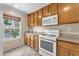 Well-lit kitchen featuring wooden cabinets, white appliances, and views of the exterior through a window at 4252 Olympic Point Dr, Las Vegas, NV 89129