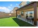 Backyard featuring a covered patio with outdoor seating, artificial grass, and privacy fence at 440 Blue Lark Dr, Henderson, NV 89011
